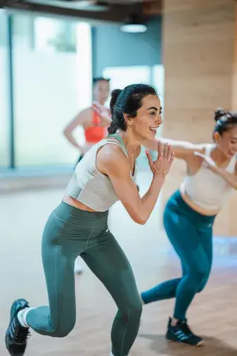 Women warming up during a BODYCOMBAT class at GymNation, preparing for a high-intensity cardio session.